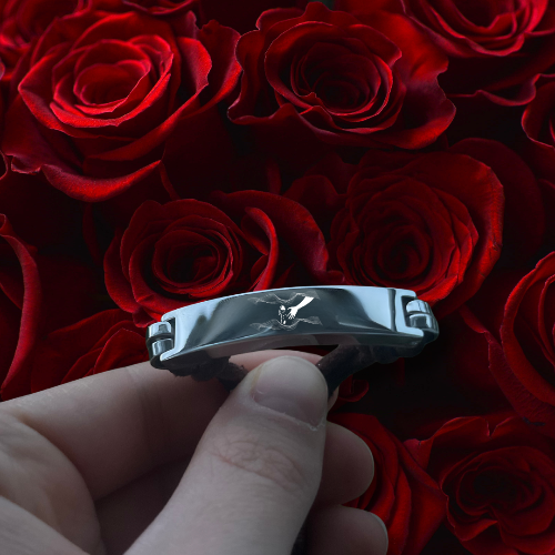 Hand holding a silver bracelet against a background of red roses