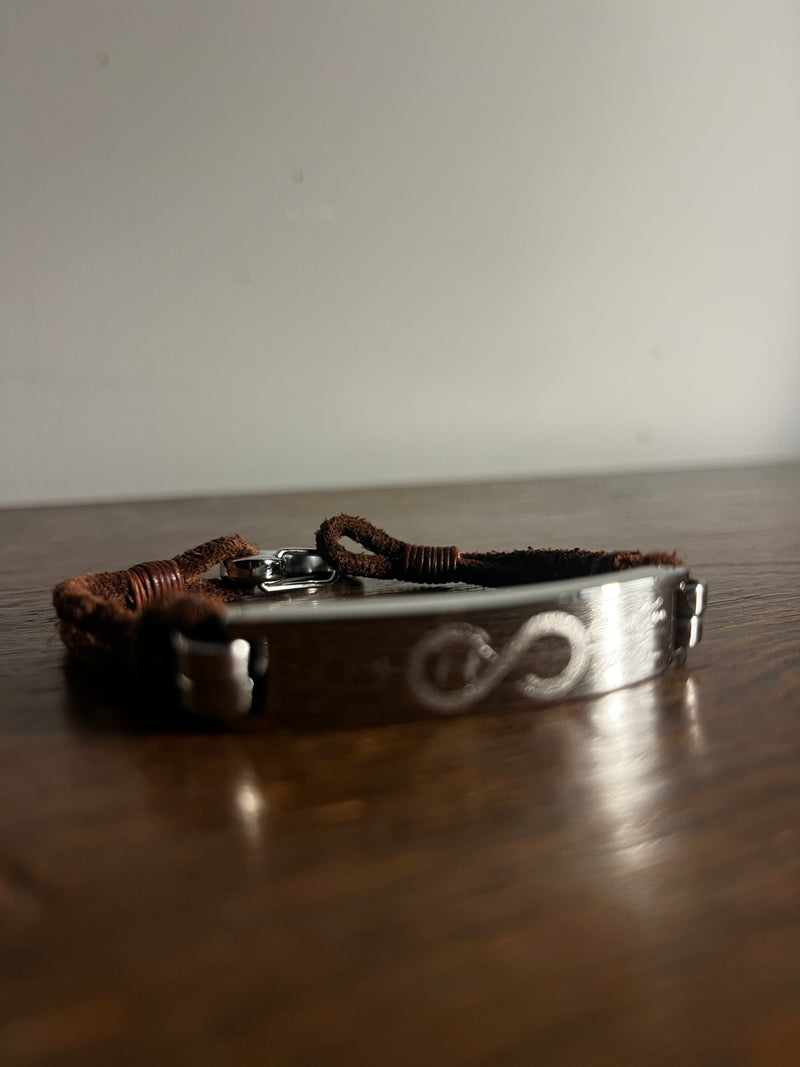 Brown leather men’s promise bracelet resting on a dark wooden surface.
