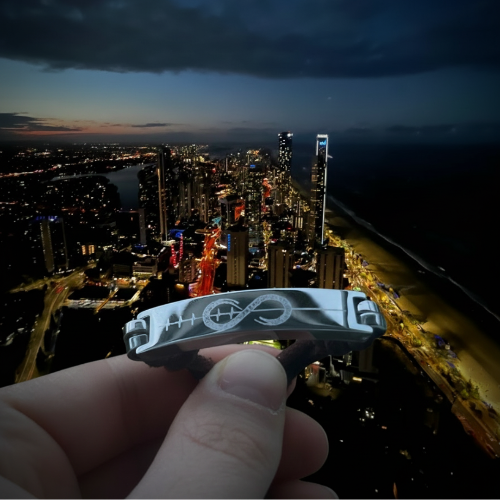 Hand holding bracelet with city at night in the background.